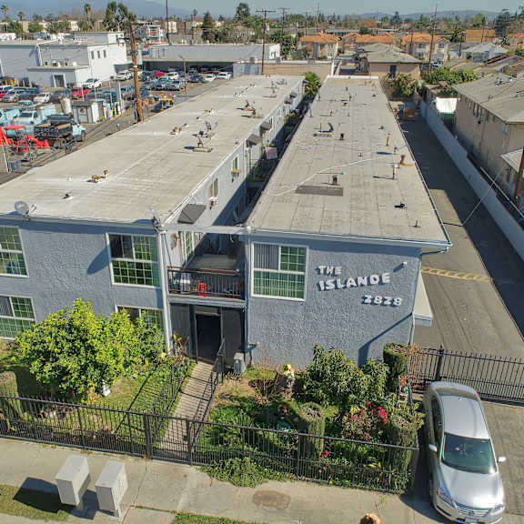a parking lot with a white van parked in front of a building with a sign that says "the island".