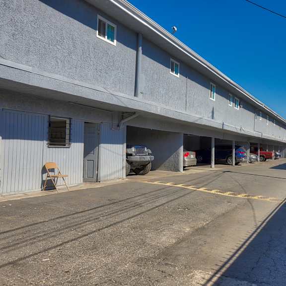 a parking lot with a building on the left and a car parked in the garage.