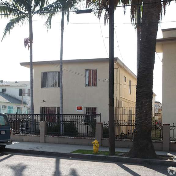a house with a black fence and a yellow fire hydrant in front.
