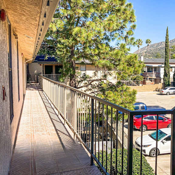 a balcony with a railing overlooks a parking lot and houses.
