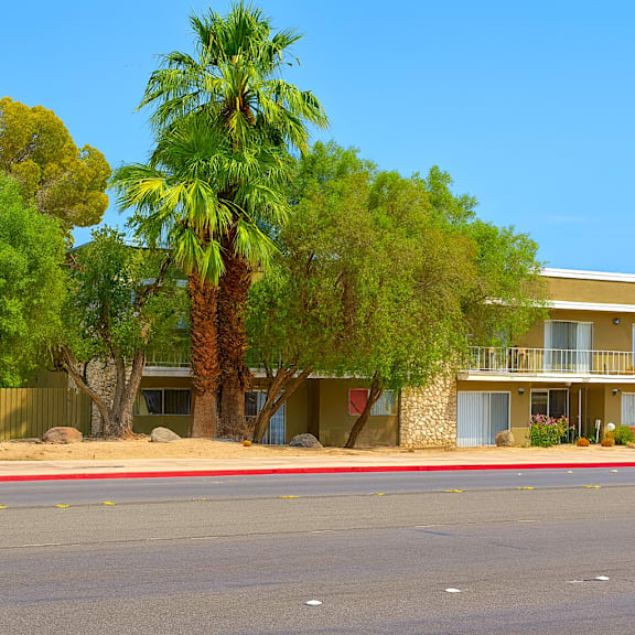 a building with a balcony and palm trees in front.