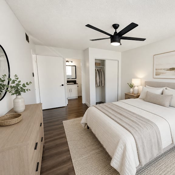 a bedroom with a large bed, a ceiling fan, and a painting on the wall.