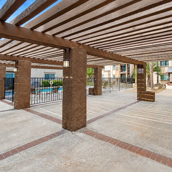 a patio with a wooden roof and concrete ground.