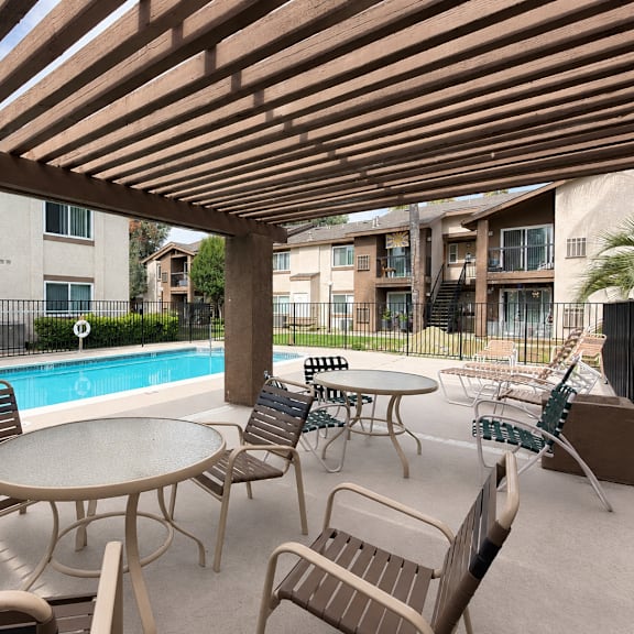 a patio with a table and chairs overlooking a pool.