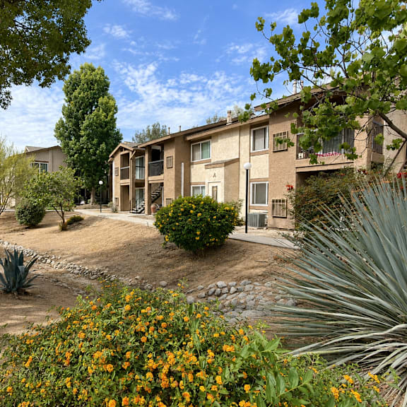 a sunny day at a residential complex with apartment buildings and flowering plants.