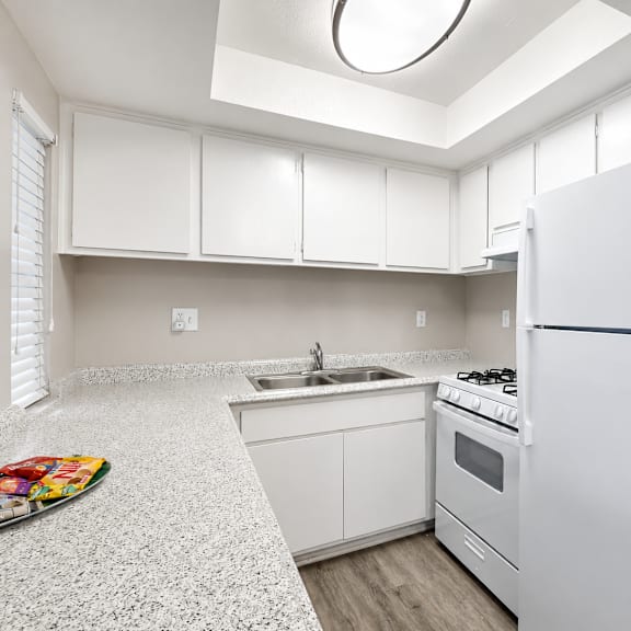 a white kitchen with a refrigerator, sink, and stove.