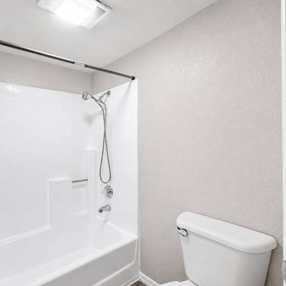 a white bathroom with a tub, toilet, and shower.