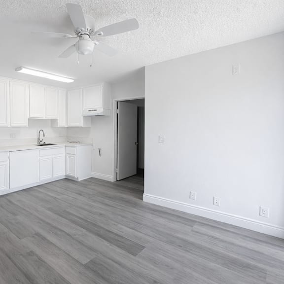 a kitchen with white cabinets and a fan on the ceiling.