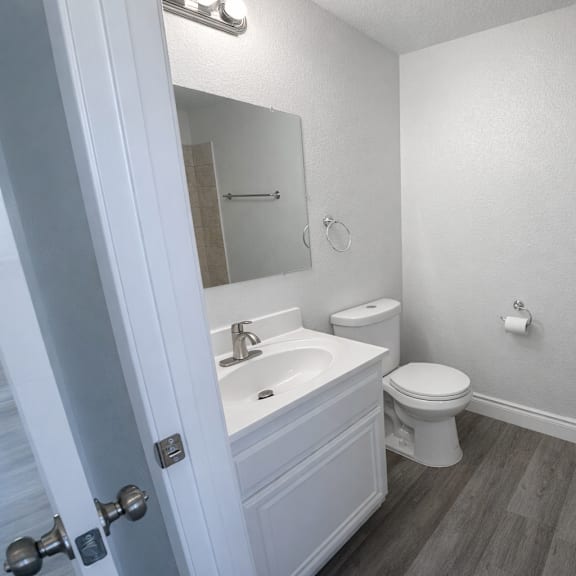 a white bathroom with a toilet, sink, and mirror.