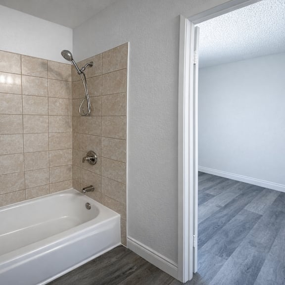 a white bathroom with a tiled shower and a white bathtub.