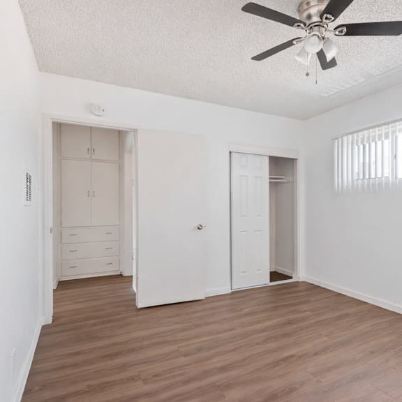 a room with a ceiling fan and wooden floors.