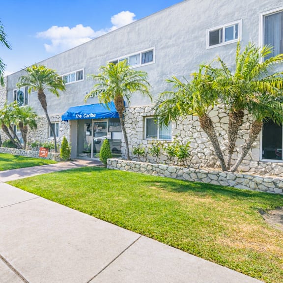 a building with a blue awning and palm trees in front.