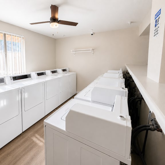 a row of white washing machines in a laundry room.