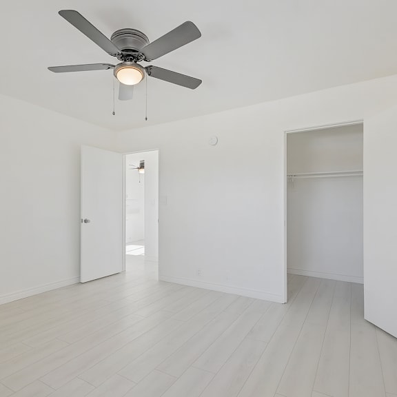 a room with a ceiling fan and white walls.