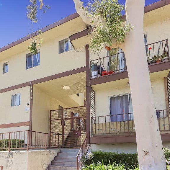 a building with a balcony and a tree in front of it.