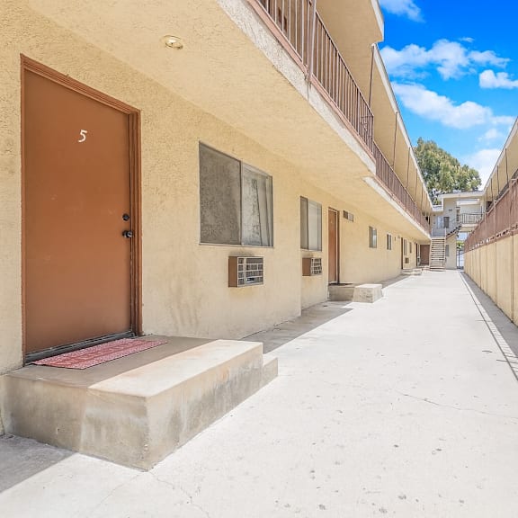 a narrow alley with a brown door on the left and a white door on the right.