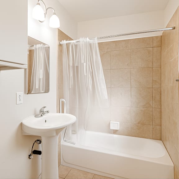 a white bathroom with a white tub, sink, and shower curtain.