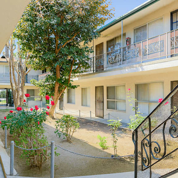 a balcony with a black railing and a tree in front of a building.