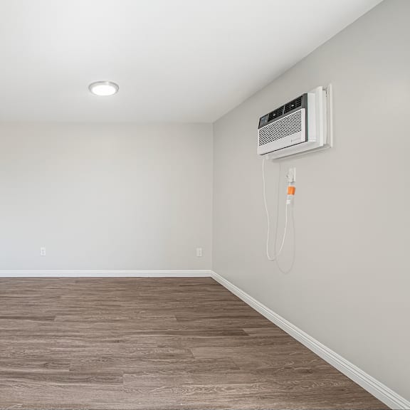 a room with a wood floor and a wall-mounted air conditioner.