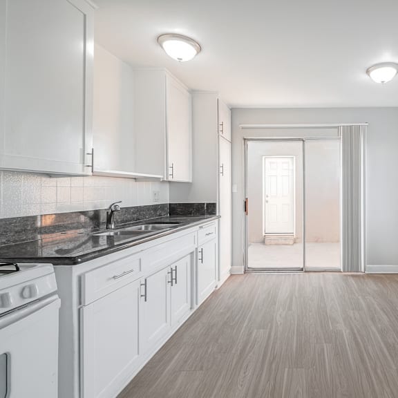 a kitchen with white cabinets and a black countertop.