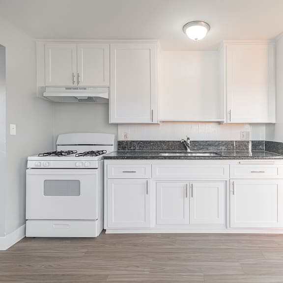a white kitchen with a stove and cabinets.