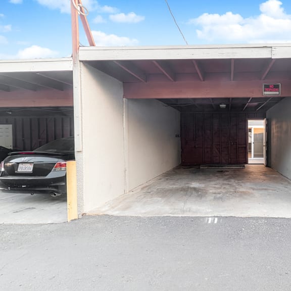 a car is parked in a garage with a white wall and a brown door.