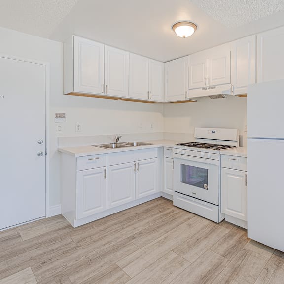 a white kitchen with a refrigerator, stove, and sink.