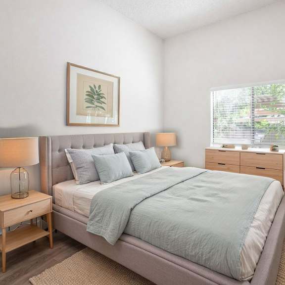 a bedroom with a bed, nightstands, and a plant.