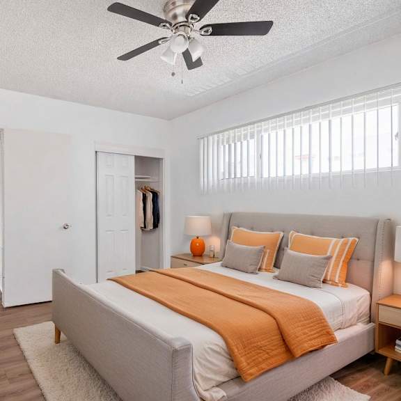 a bedroom with a bed, a ceiling fan, and a wooden nightstand.