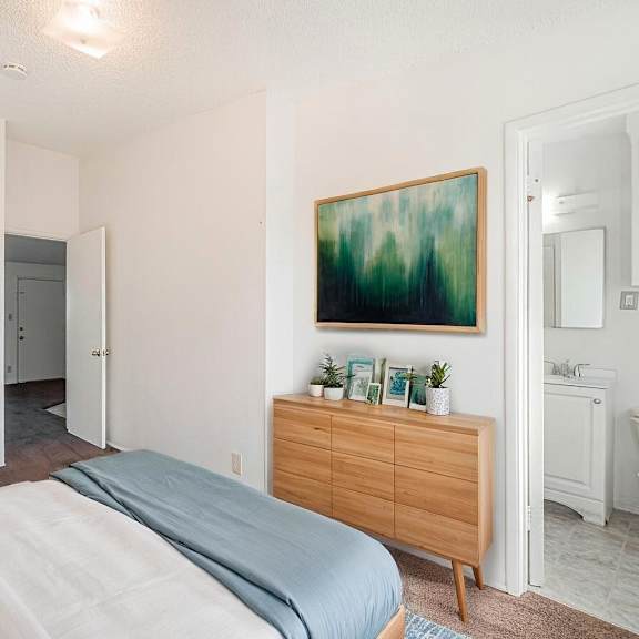 a bedroom with a bed, a dresser, and a painting on the wall.