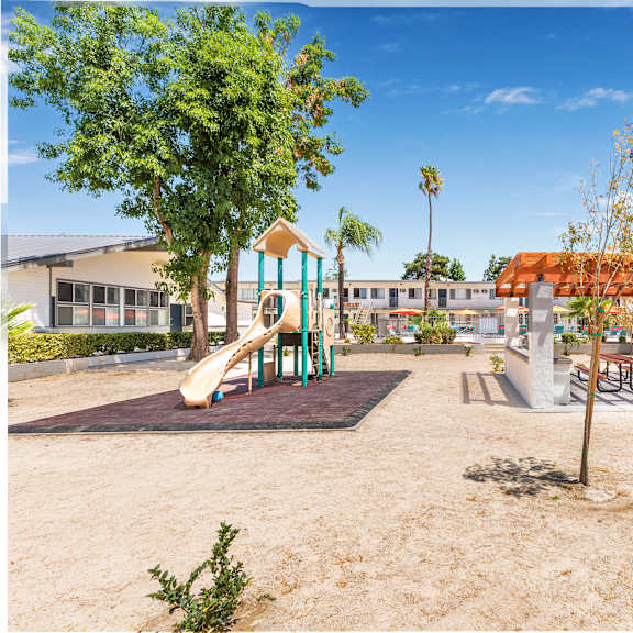 a playground with a slide, swings, and a picnic table.