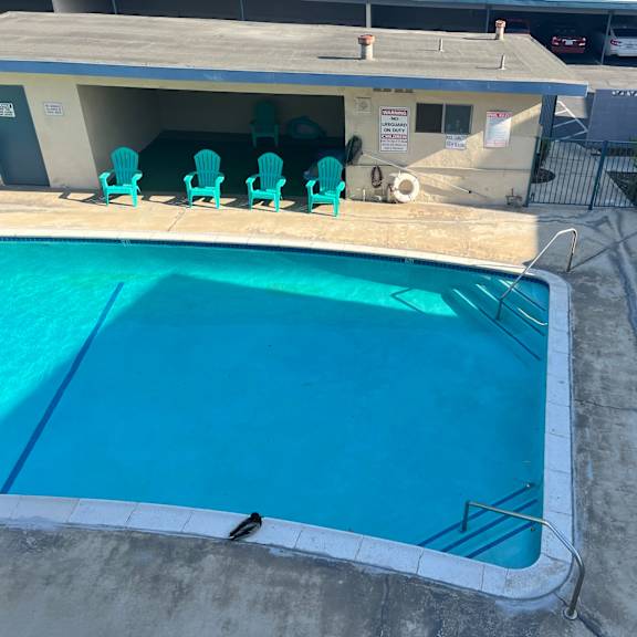 a pool with a diving board and chairs around it.