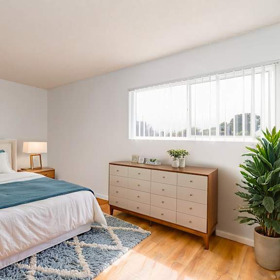 a bedroom with a bed, nightstands, and a plant.
