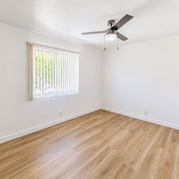 a room with a ceiling fan and a window with blinds.
