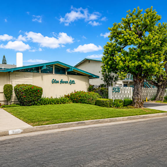 a building with a green awning and a sign that says "garden inn" is surrounded by a well-manicured lawn and a sidewalk.
