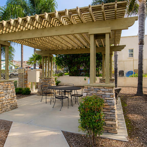 a patio with a table and chairs under a wooden pergola.