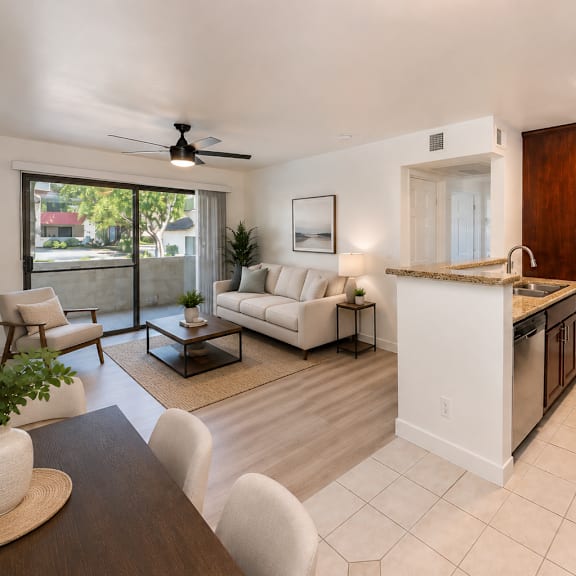 a modern kitchen and living room with white furniture and a ceiling fan.
