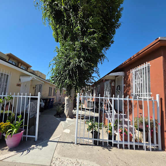 a white fence surrounds a courtyard with potted plants.