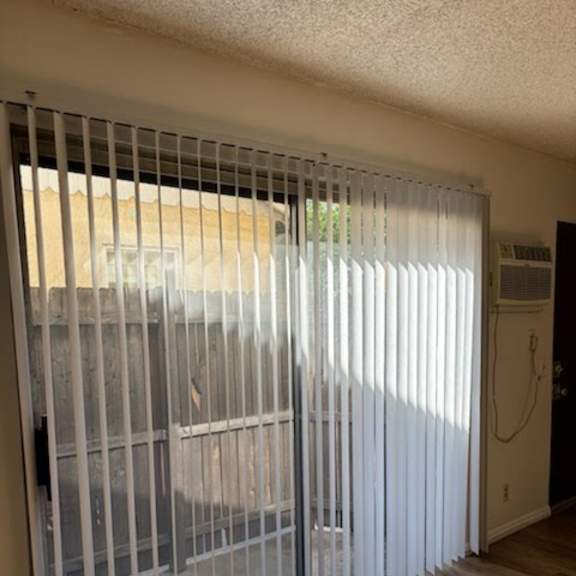 a room with a sliding door covered with vertical blinds.
