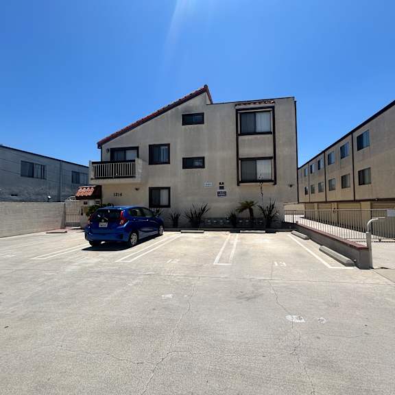 a blue car is parked in a parking lot in front of a building.