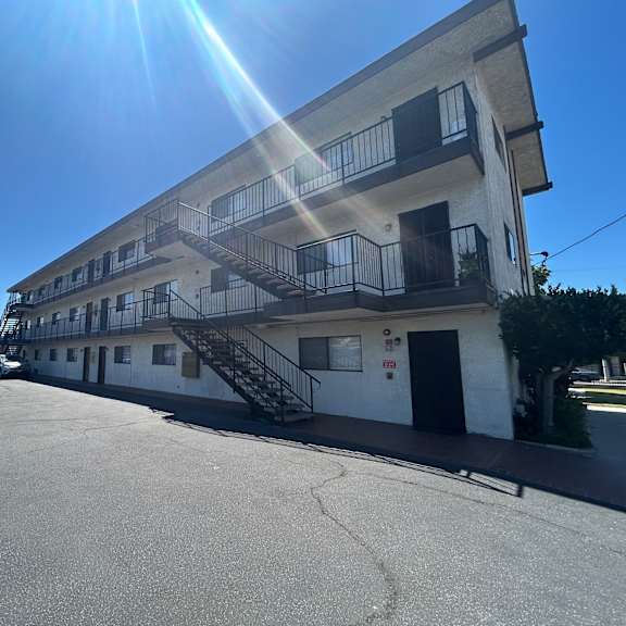 a sunny day at a parking lot with a building in the background.