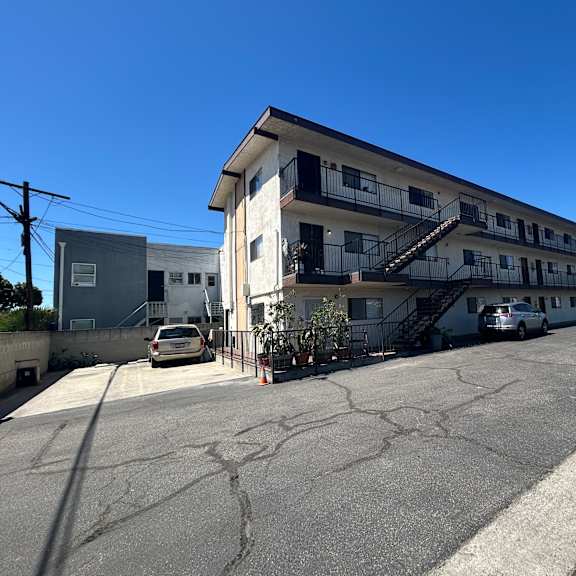 a parking lot with a white building and a car parked in front.