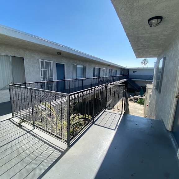 a balcony with a metal railing and a cage with a cat inside.