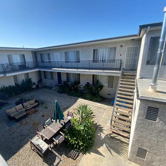 a patio with a table and chairs is surrounded by a building.