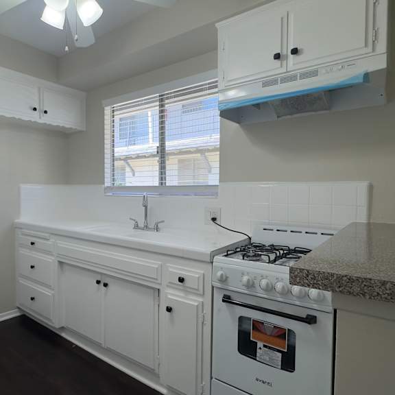 a white kitchen with a fridge, stove, and sink.
