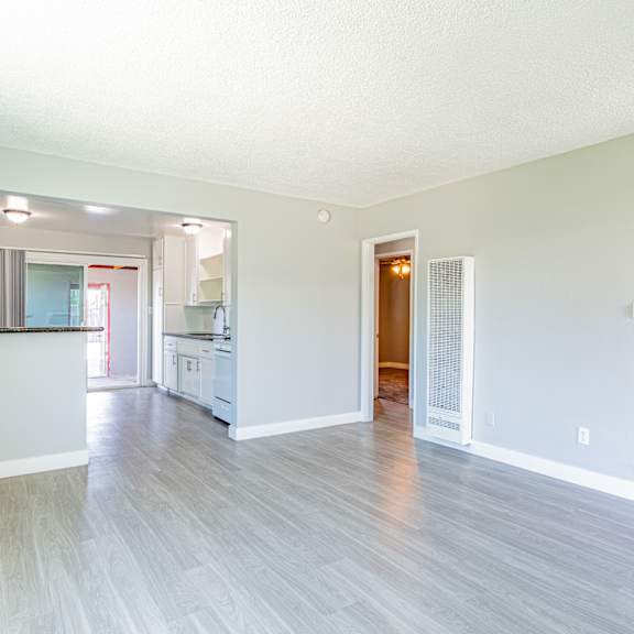 a spacious living room with a kitchen in the background.