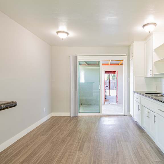 a kitchen with white cabinets and a wooden floor.