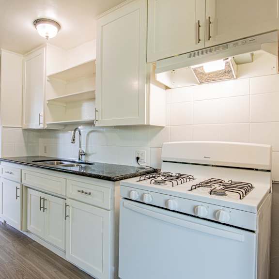 a white kitchen with a stove and cabinets.