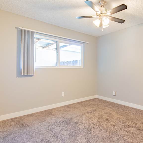 a room with a ceiling fan and carpeted floor.