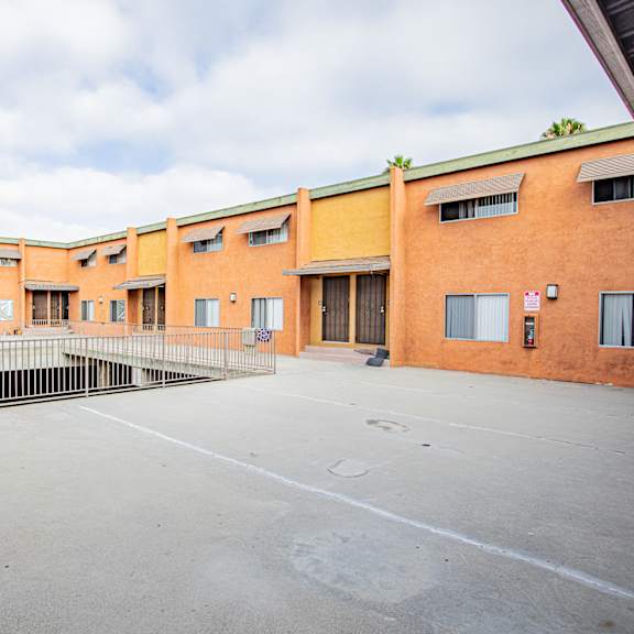 a parking lot in front of a building with orange walls.